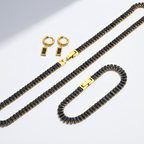 Jewelry set with black beaded necklace and earrings on a light gray background