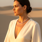 Woman wearing a white garment and pearl necklace against a desert backdrop
