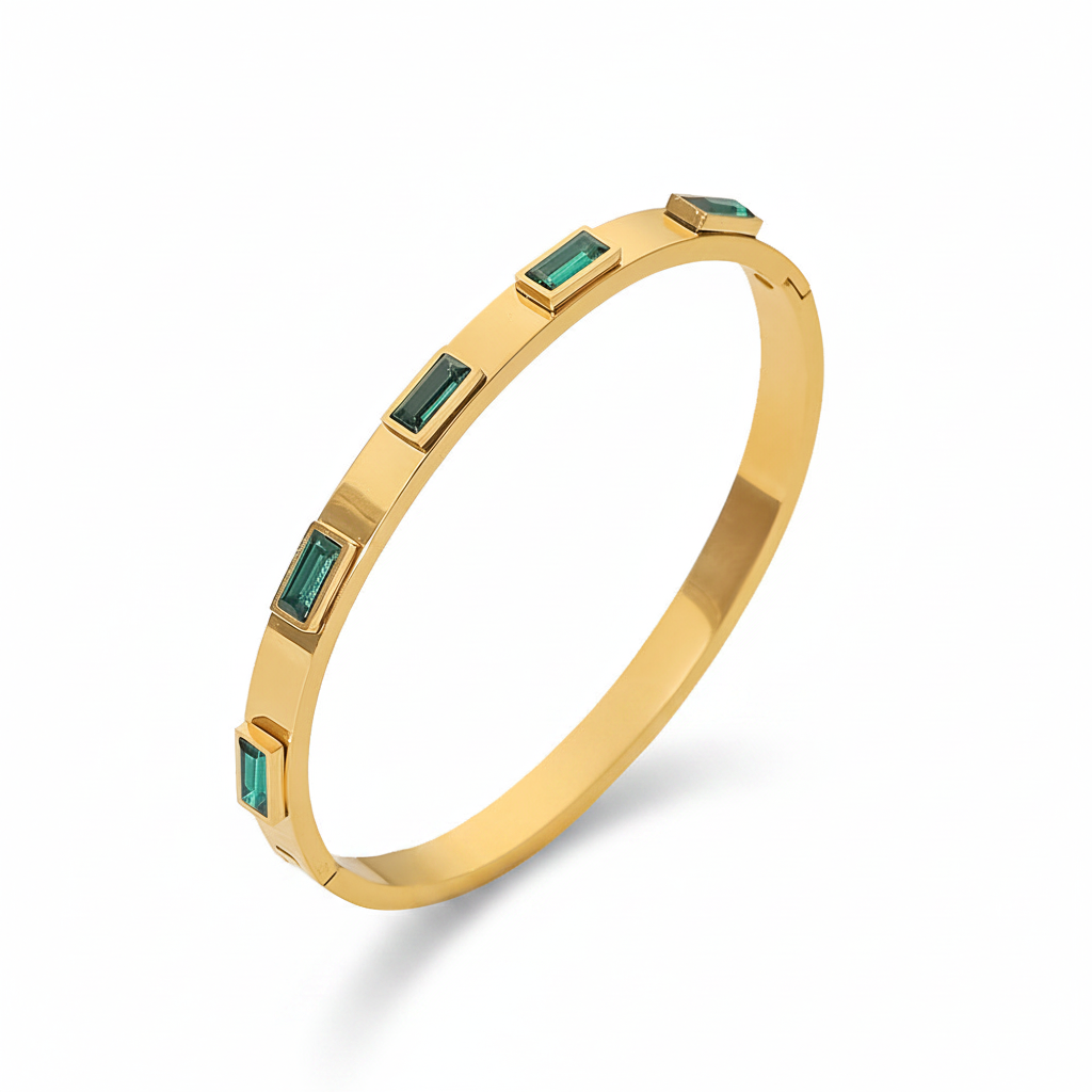 Gold bracelet with emerald green stones on a white background