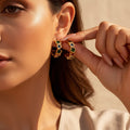 The Accessory Bar The Bana gold-plated C-hoop earrings with colourful cubic zirconia stones worn by a woman.
