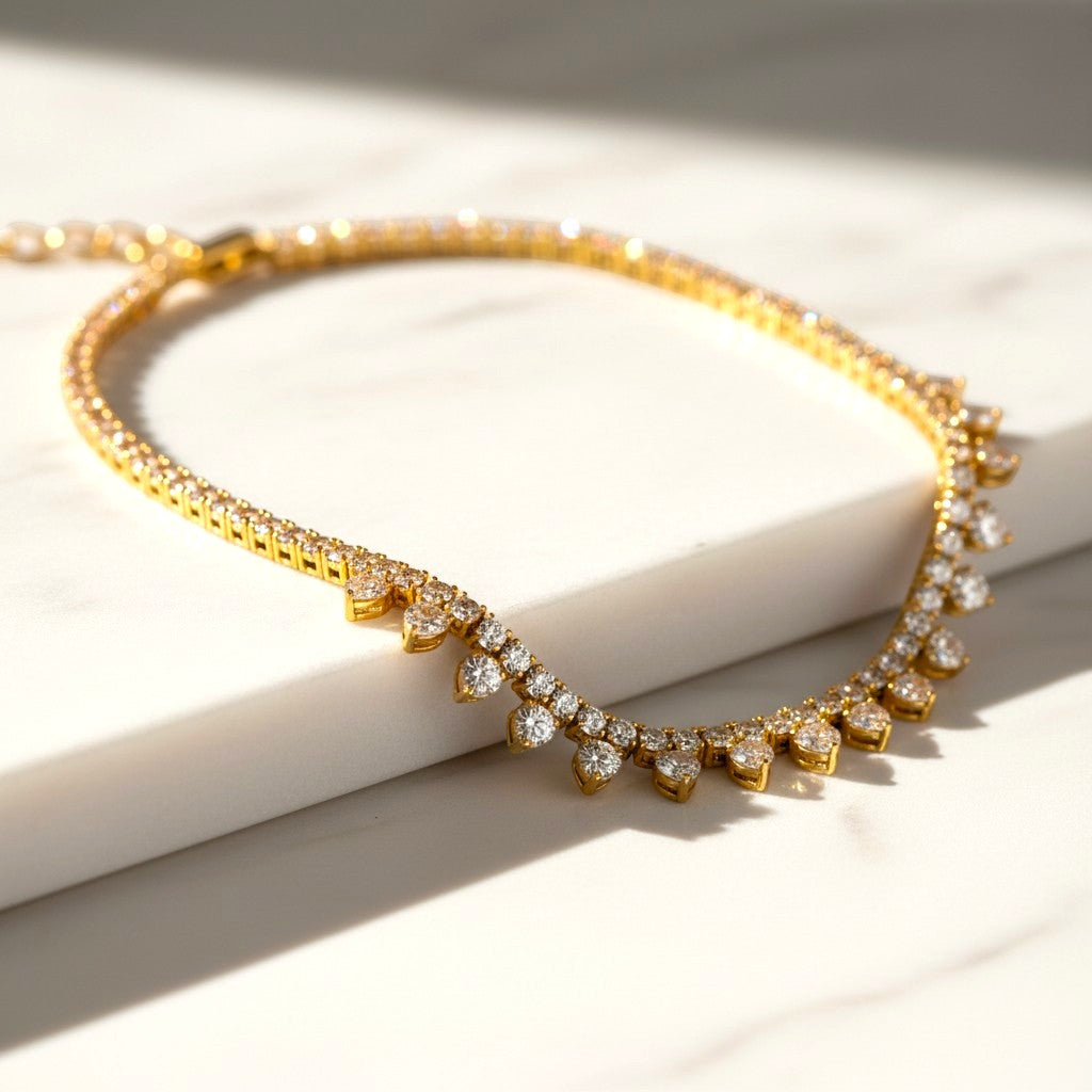 The Accessory Bar gold-plated heart-detail tennis choker with pavé-set cubic zirconia on a white marble surface.