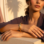 The Accessory Bar Lina gold-plated open cuff bracelet with a bezel-set white cubic zirconia stone on a model's wrist.