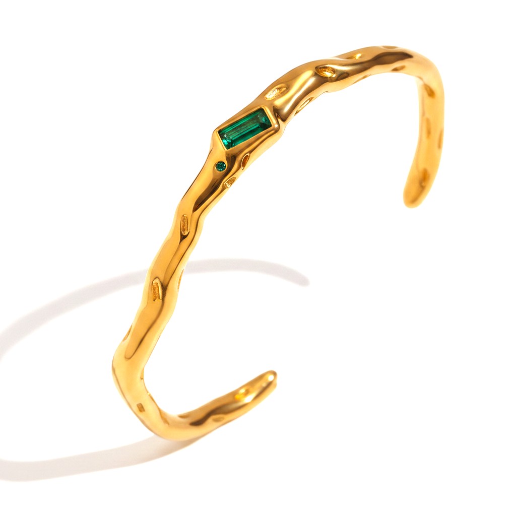 The Accessory Bar Lina gold-plated open cuff bracelet with a bezel-set emerald green cubic zirconia stone.