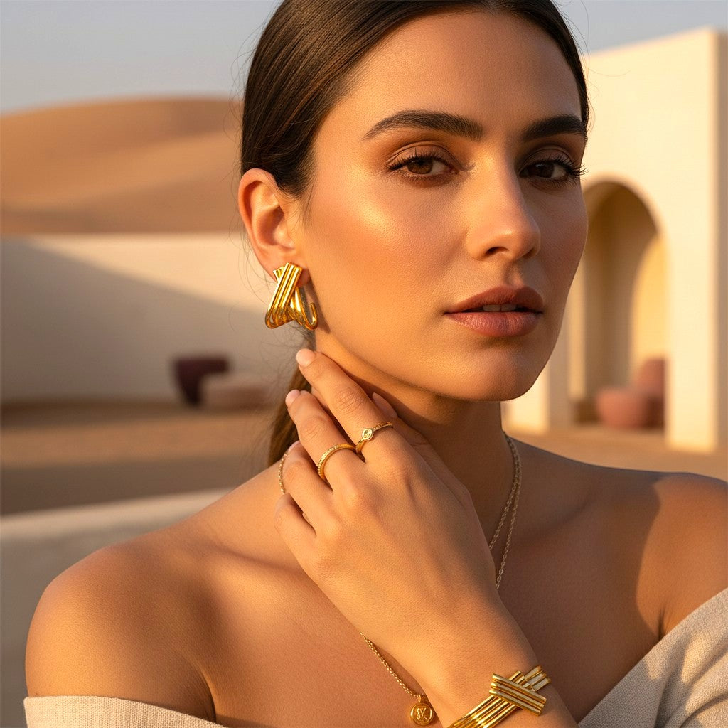 Model wearing The Accessory Bar Lyra ribbed 18K gold-plated earrings in a desert setting.