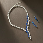 The Accessory Bar Nadia set featuring a silver-tone tennis necklace and matching earrings with blue and clear stones.
