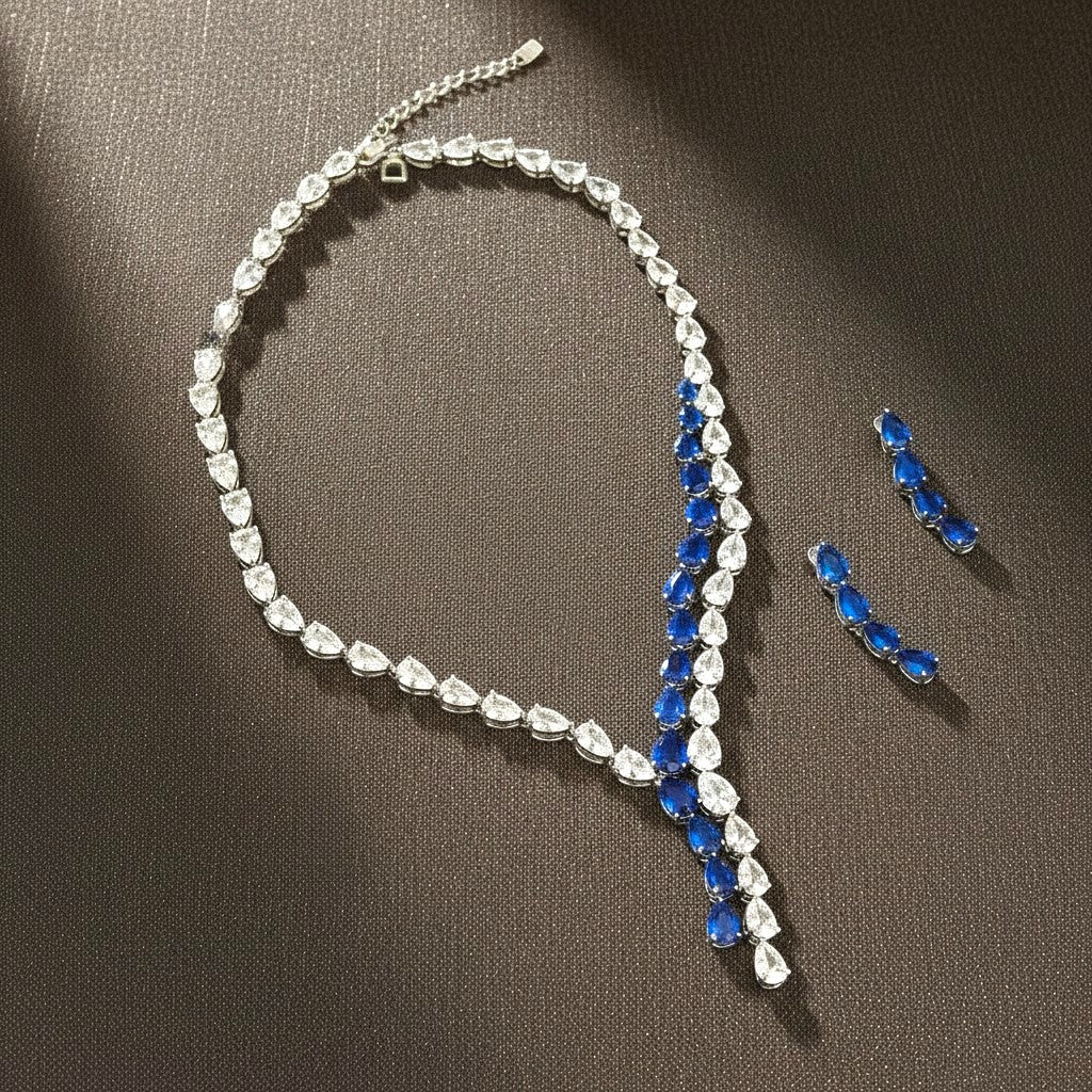 The Accessory Bar Nadia set featuring a silver-tone tennis necklace and matching earrings with blue and clear stones.