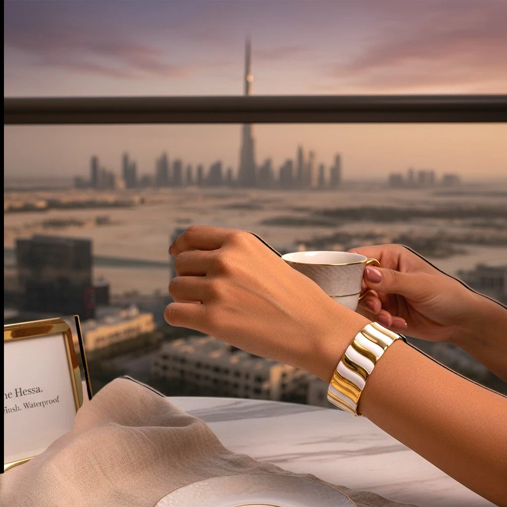 The Accessory Bar Sama wide ribbed cuff in dual-tone 18K gold and silver stainless steel worn against a Dubai skyline.