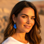Model wearing The Accessory Bar Zara gold-plated drop earrings with a bold blue cubic zirconia stone at sunset.